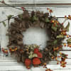Autumn wreath with red berries and orange pods on a rustic wood ring