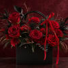 Red roses arranged in a black gift box with a red ribbon