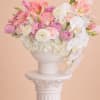 Pink and white floral arrangement in a white pedestal vase