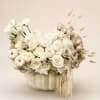 Cream rose arrangement in a white pumpkin container with dried accents
