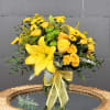 Yellow floral arrangement in a glass vase with a ribbon