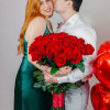 Couple holding a large bouquet of red roses with red heart balloons
