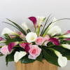 Pink roses and white-purple calla lilies in a wooden container
