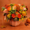 Autumn bouquet of orange and yellow roses in a pumpkin vase