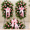 Three floral standing sprays with pink and white flowers and pink ribbons