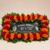 Red roses and orange marigolds arranged around a memorial plaque