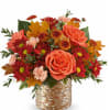 Orange roses and red daisies in a woven basket with autumn leaves