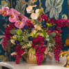 Pink orchids and magenta flowers arranged in a gold vase