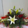Low floral centerpiece with white lilies, red roses, and red ribbon