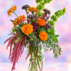 Tall mixed bouquet with orange and gray flowers in a clear glass vase