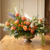 Mixed floral arrangement in a silver pedestal bowl on a wooden table
