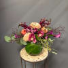 Mixed floral arrangement in a round green glass vase