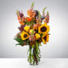 Tall mixed bouquet with sunflowers and roses in a clear glass vase