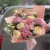 Pink and cream bouquet of roses and hydrangeas wrapped in blush paper