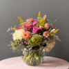 Mixed bouquet in a clear glass vase with pink, peach, white, and yellow blooms