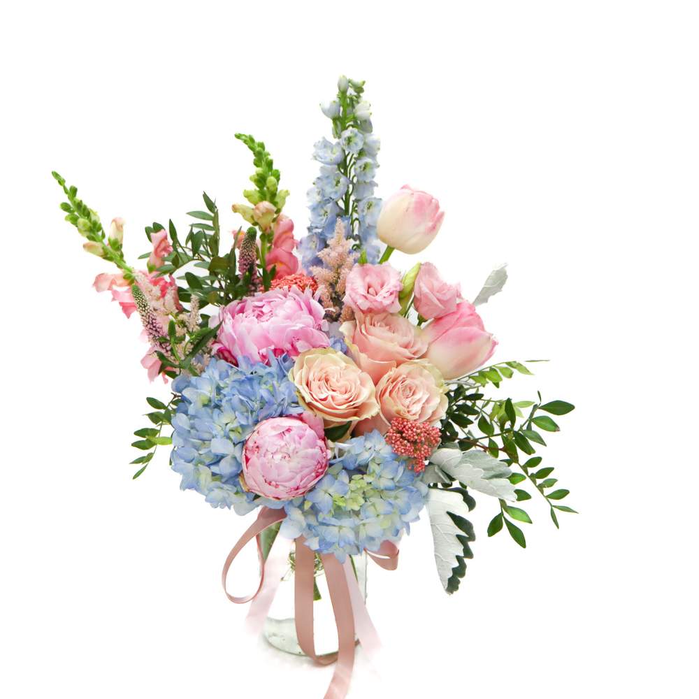 Pastel bouquet of roses, peonies, hydrangeas, and snapdragons in a glass vase