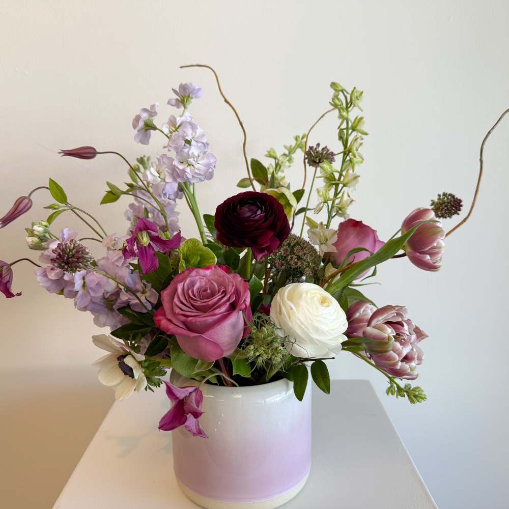 Mixed pink, white, and lavender flowers in a white vase