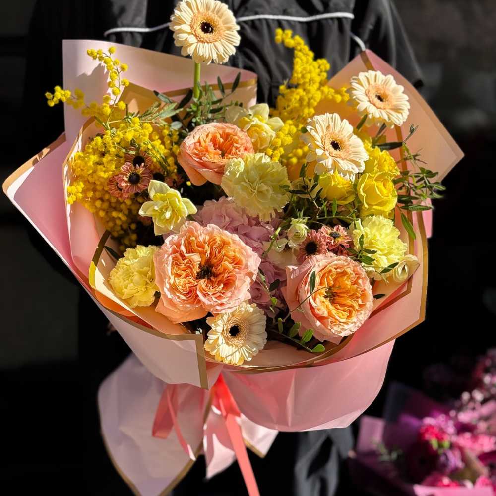 Pink and yellow bouquet with gerbera daisies and carnations wrapped in pastel paper
