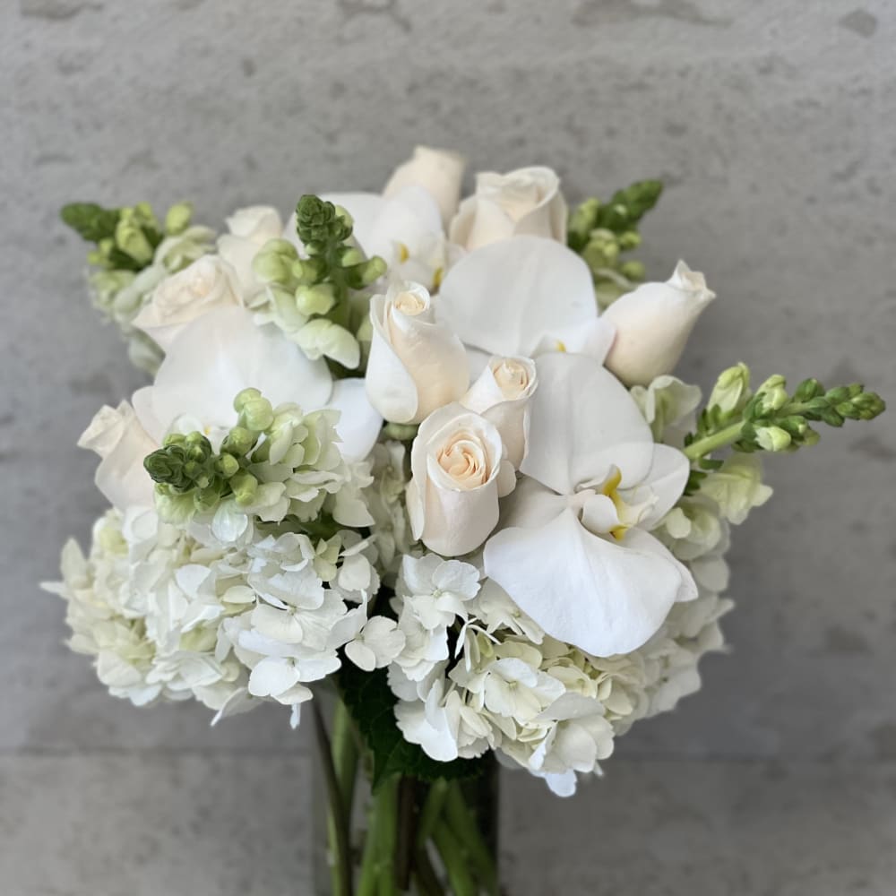 White roses and orchids arranged in a glass vase