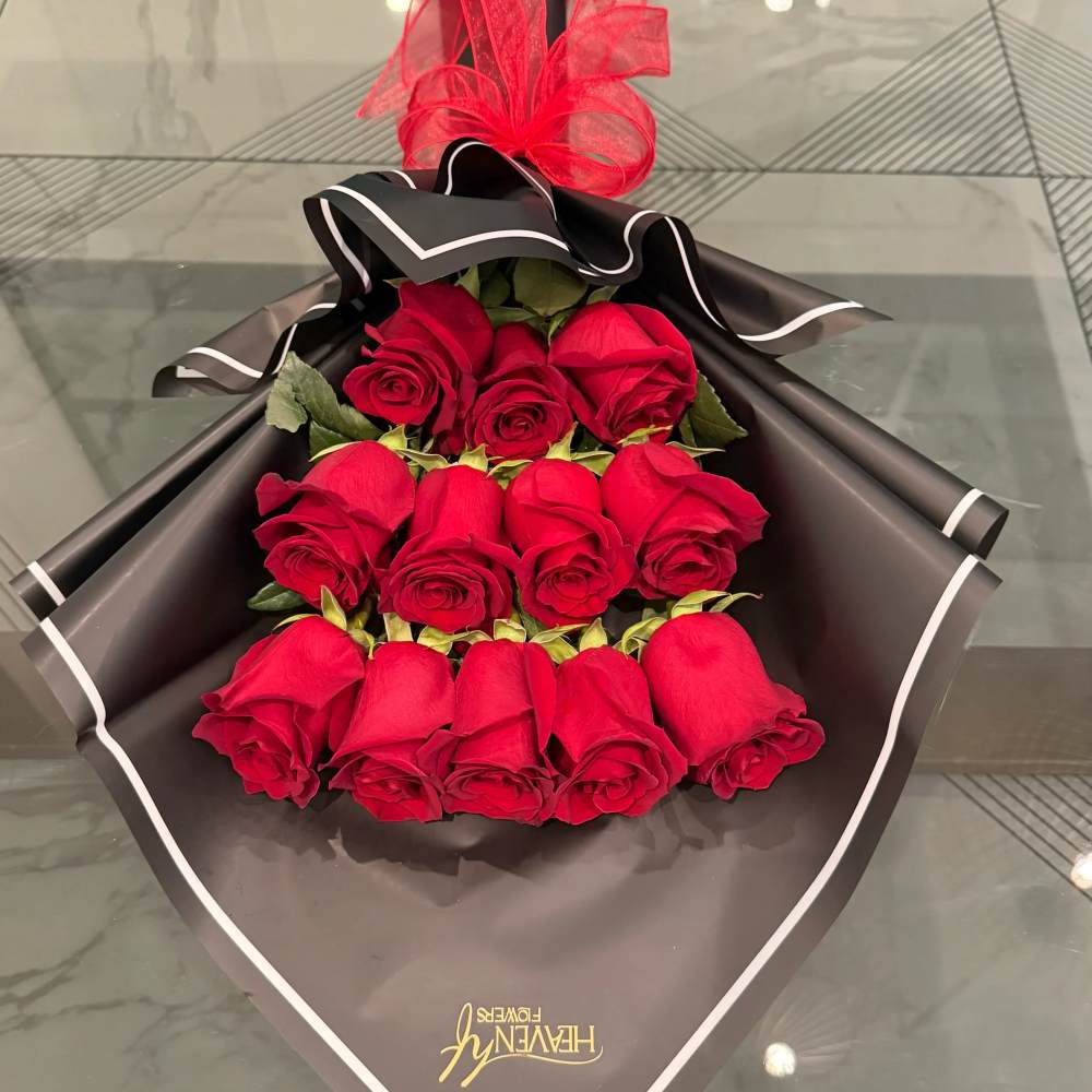Bouquet of red roses wrapped in black paper with a red bow