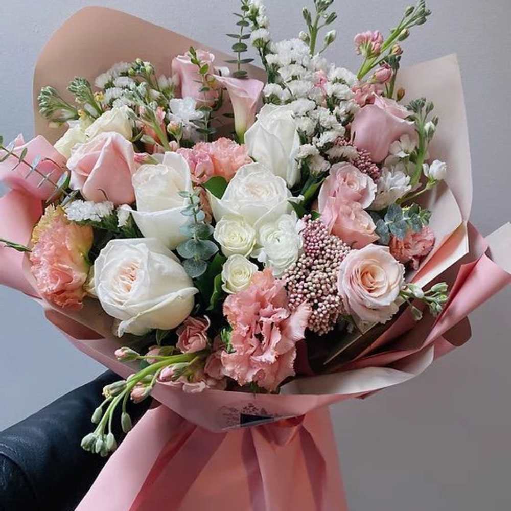 Hand-tied bouquet of pink and white roses with pink wrapping