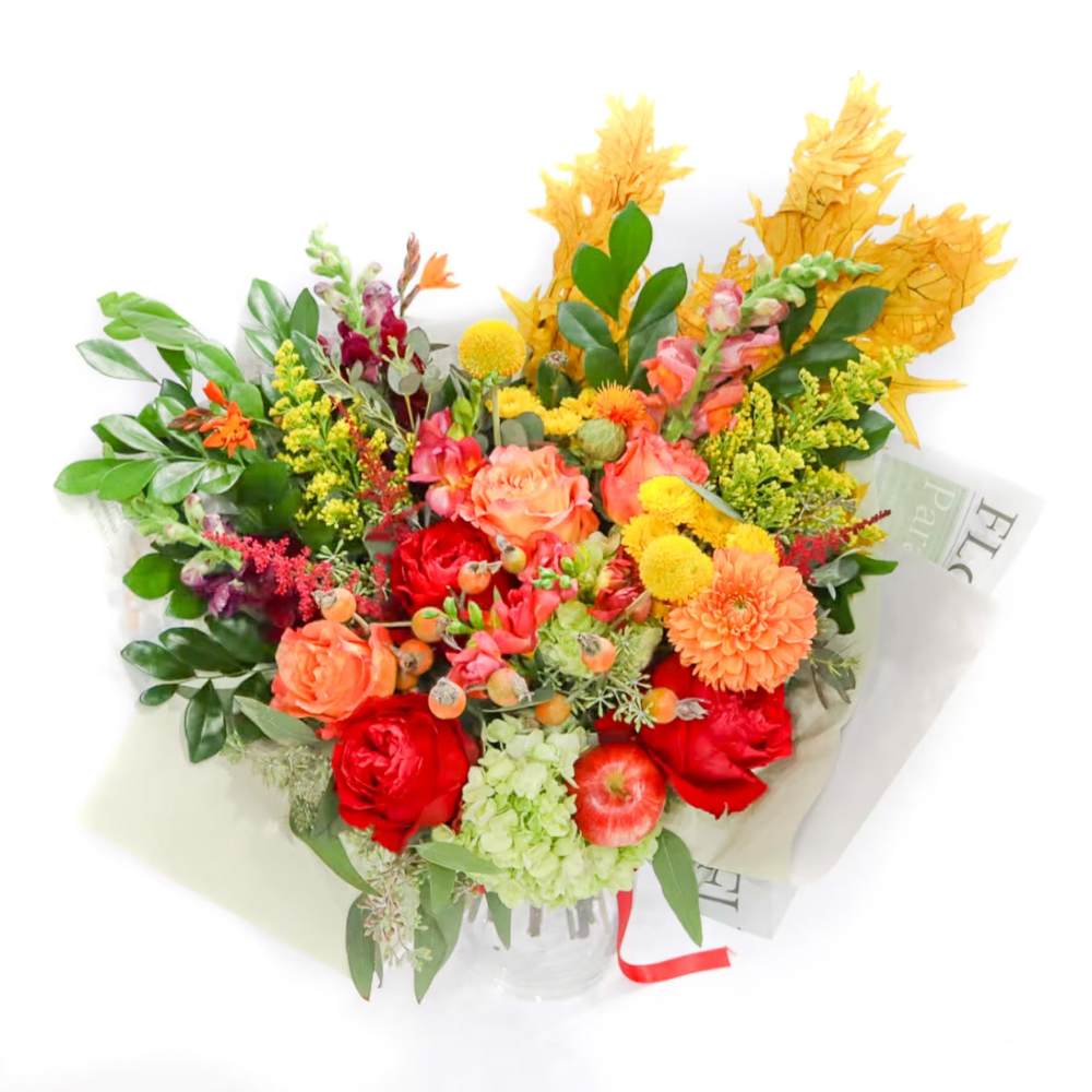 Mixed bouquet of red, orange, and yellow flowers in a clear vase