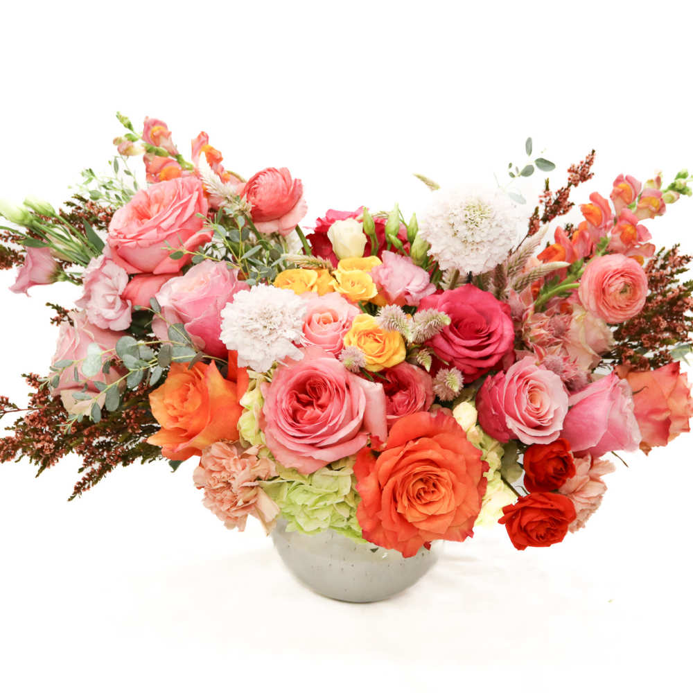 Mixed pink and orange flower arrangement in a round vase