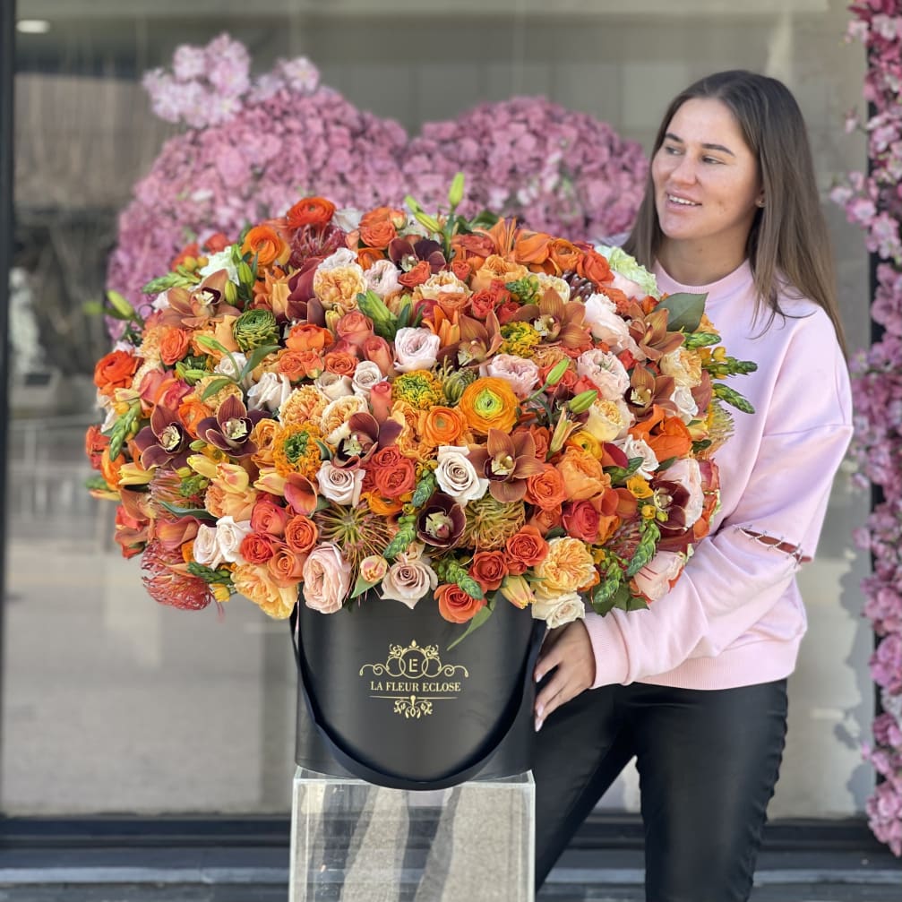 Woman holding a large mixed bouquet in a black hatbox