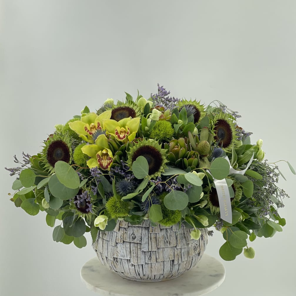 Large green floral arrangement in a textured white vase