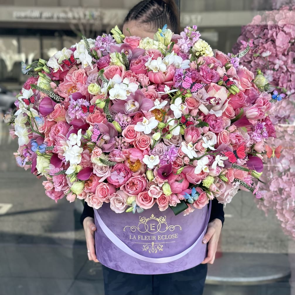 Large pink and white flower arrangement in a purple hat box