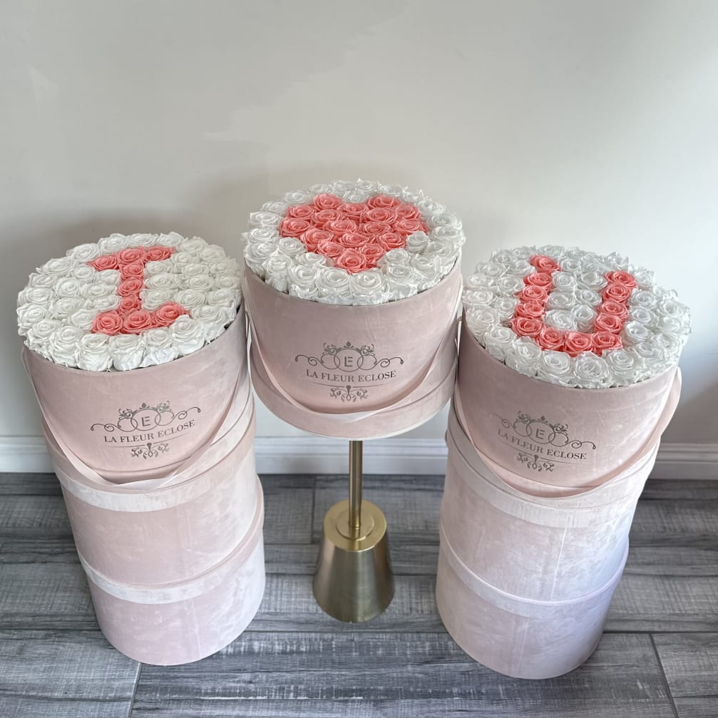 Three pink hat boxes filled with white and pink roses, one with a heart design.