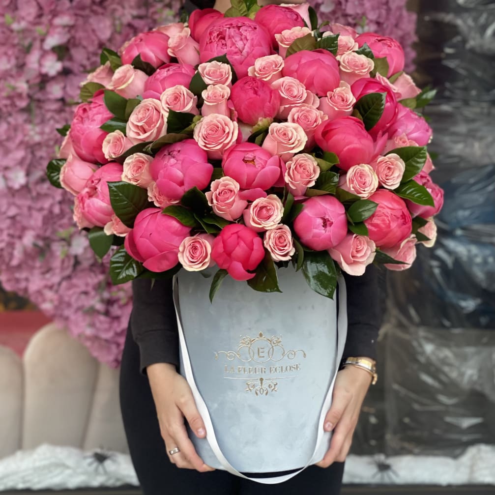 Pink peonies and spray roses in a pale blue hatbox