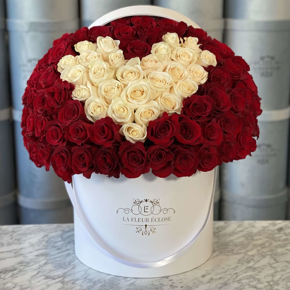 Heart-shaped red and cream rose arrangement in a white hat box