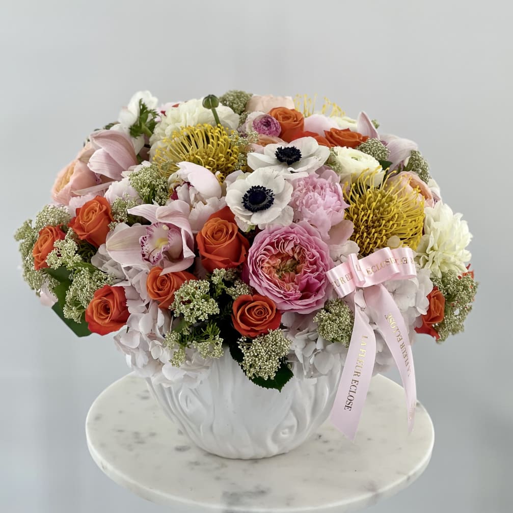 Mixed bouquet in a white vase with pink, orange, yellow, and white flowers