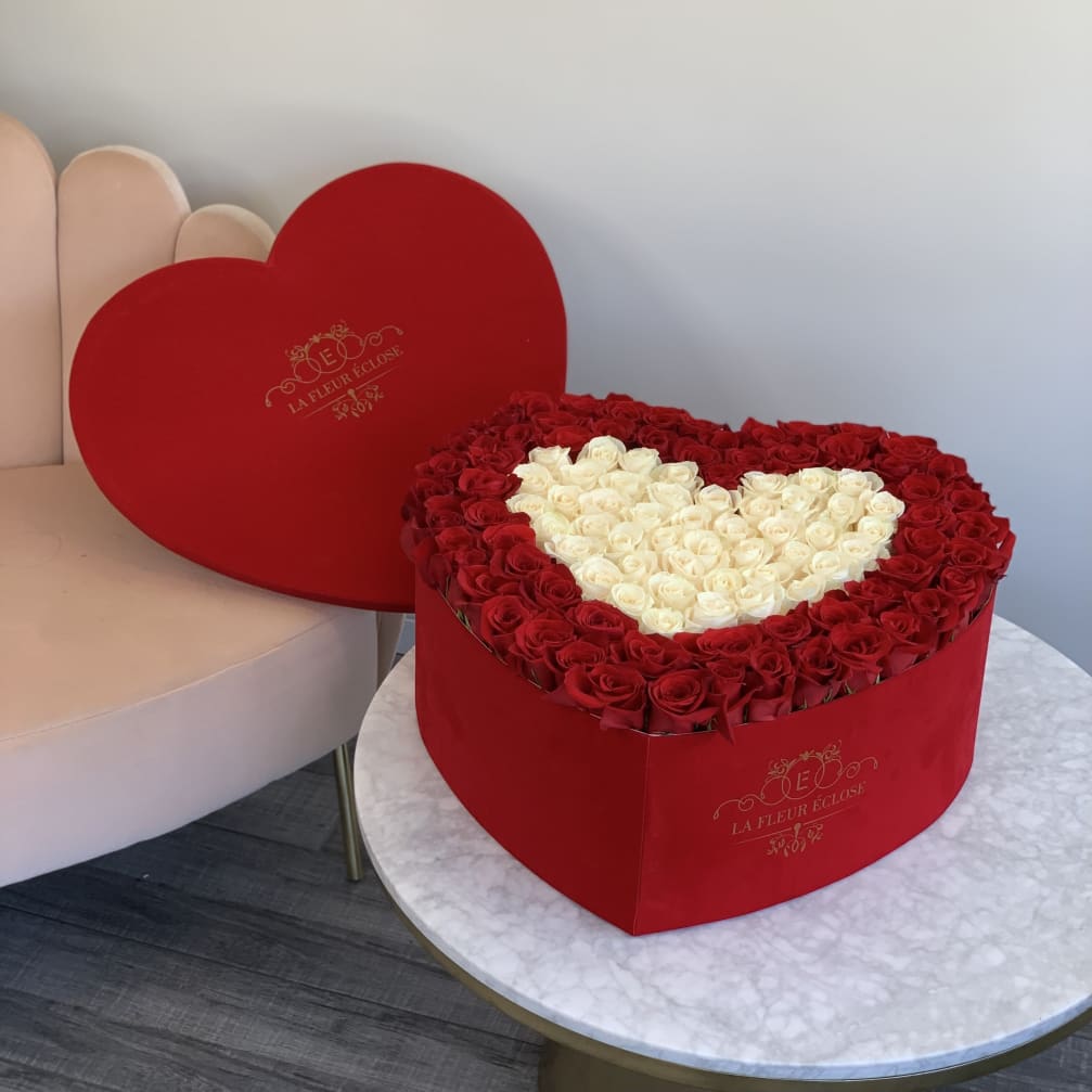 Heart-shaped box of red and white roses on a table
