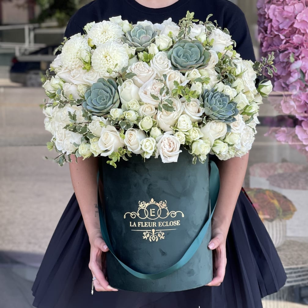 Large white rose and succulent arrangement in a dark green hatbox
