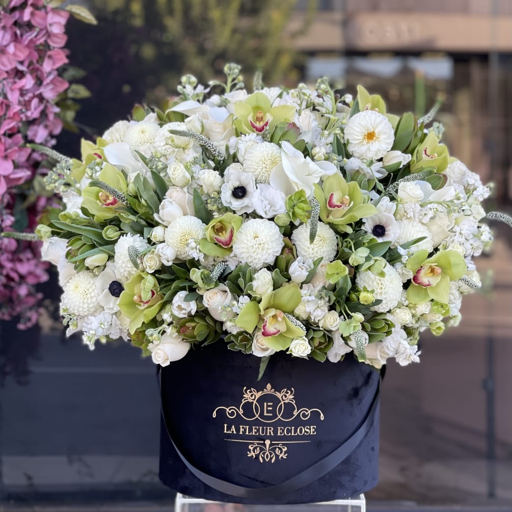 Large white and green floral arrangement in a black hatbox