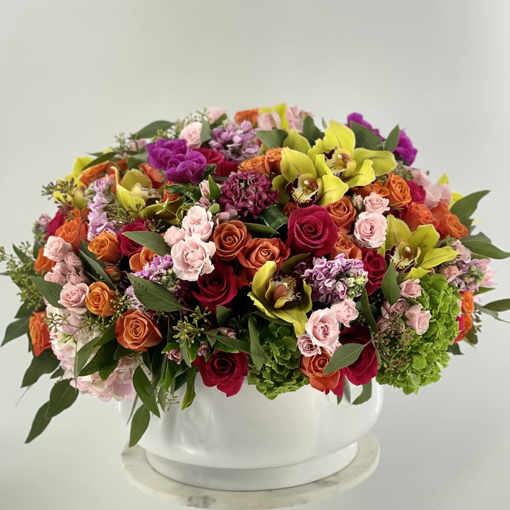 Mixed bouquet in a white vase with roses and yellow orchids