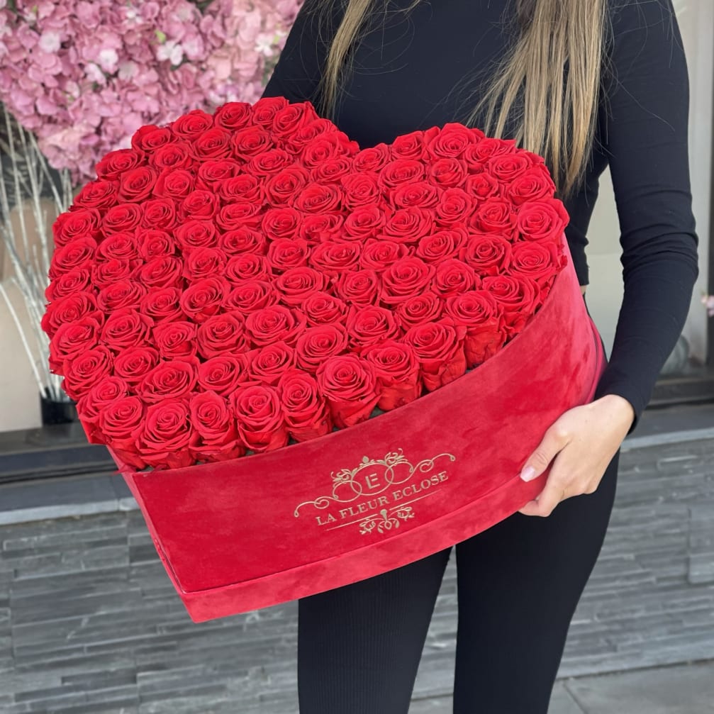 Heart-shaped box of red roses held by a person