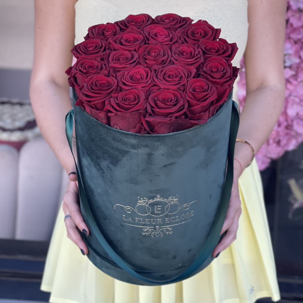 Bouquet of deep pink roses in a teal hatbox