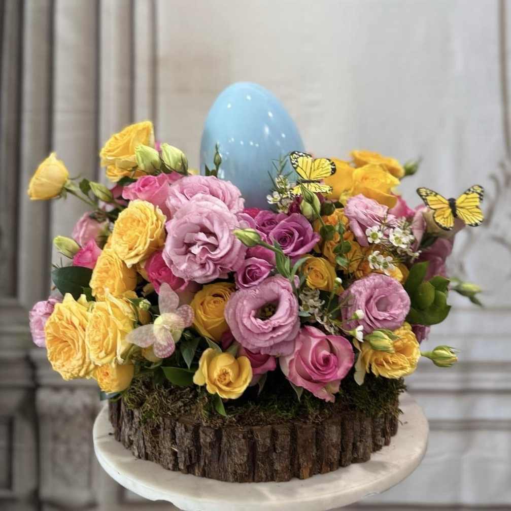 Pink and yellow roses arranged around a blue egg centerpiece