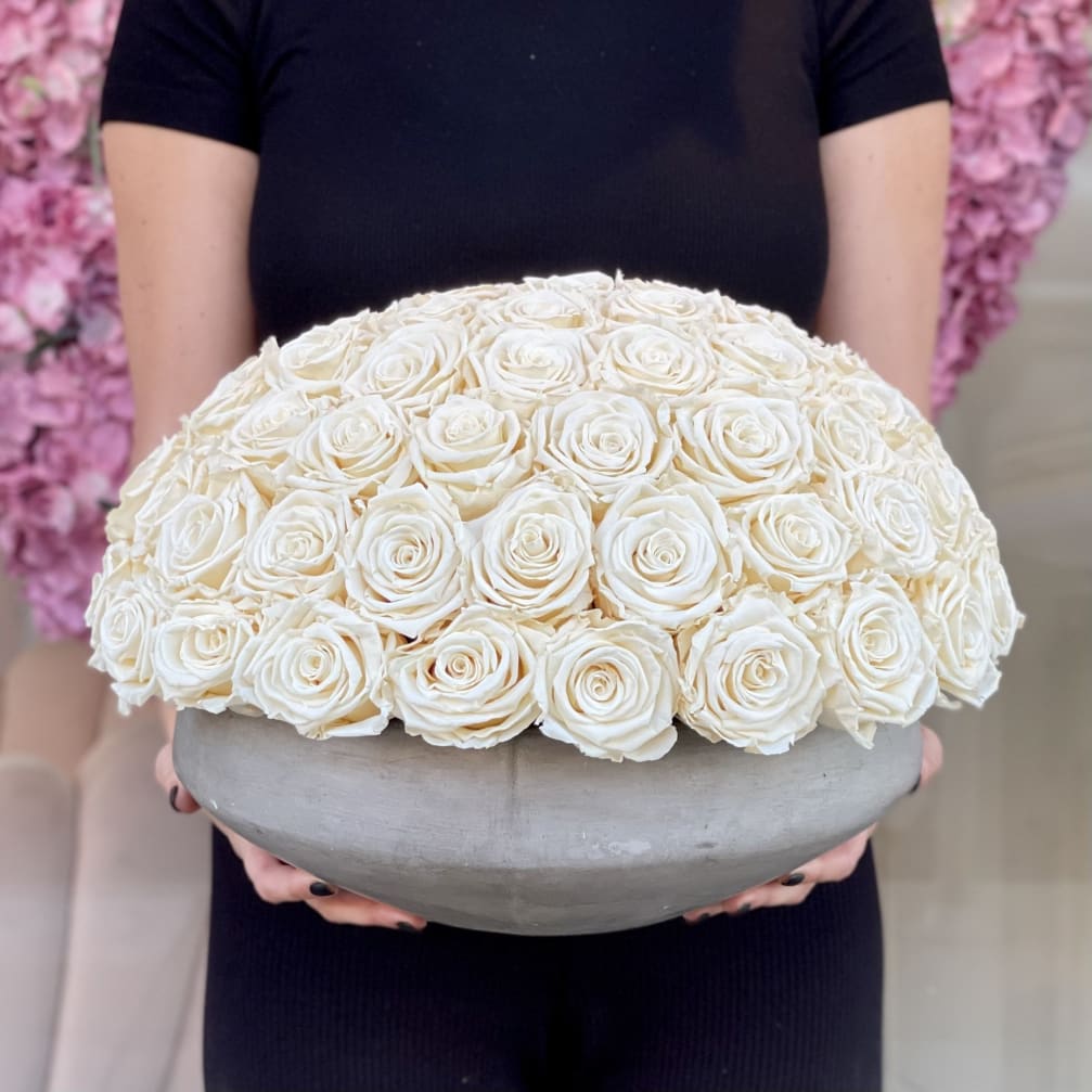 Large dome of white roses in a gray bowl vase