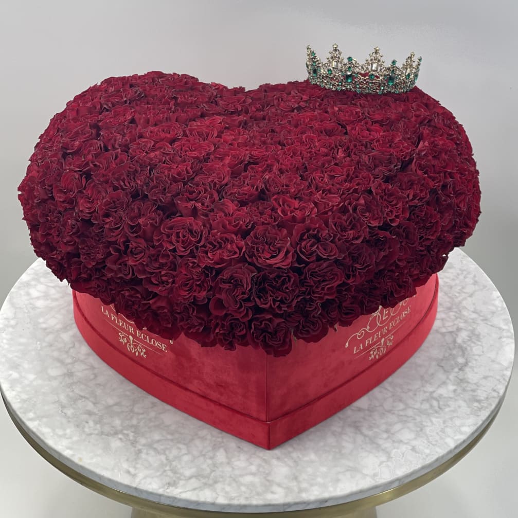 Heart-shaped box filled with deep red roses and a jeweled crown topper