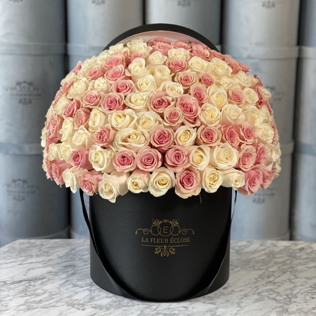 Round bouquet of pink and cream roses in a black hatbox