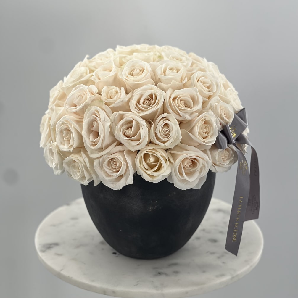 Cream rose bouquet in a black vase with a gray ribbon