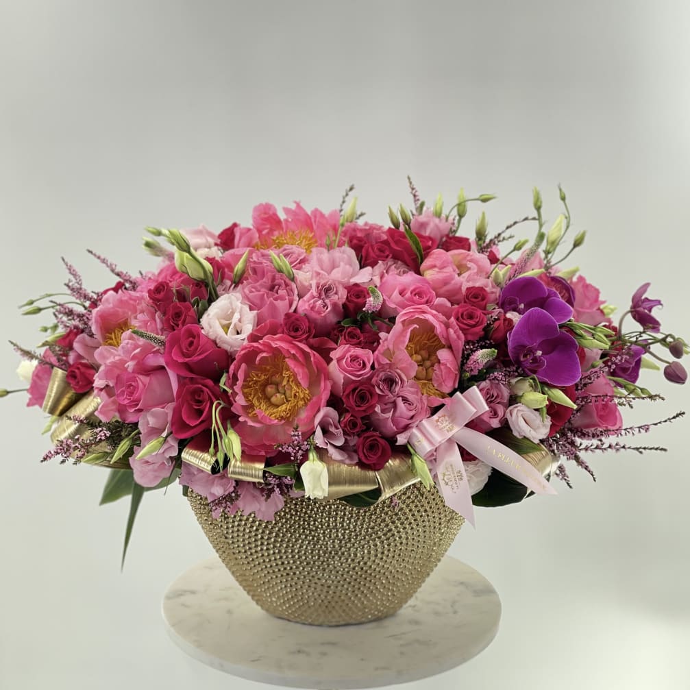Pink and purple flower arrangement in a gold textured vase