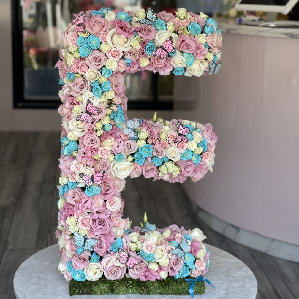 Large letter E covered in pastel roses with butterfly accents