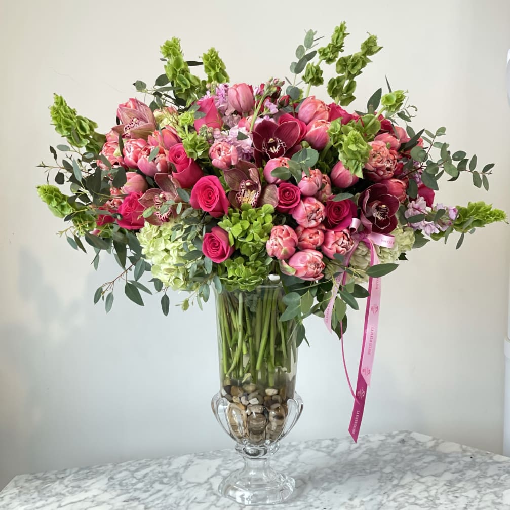 Pink and burgundy flower arrangement in a clear glass vase