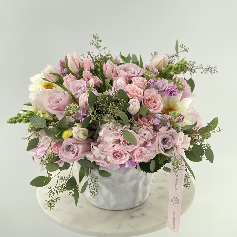 Pink and lavender rose bouquet in a white vase