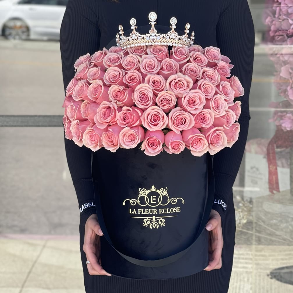 Large bouquet of pink roses in a black hatbox with a jeweled crown topper